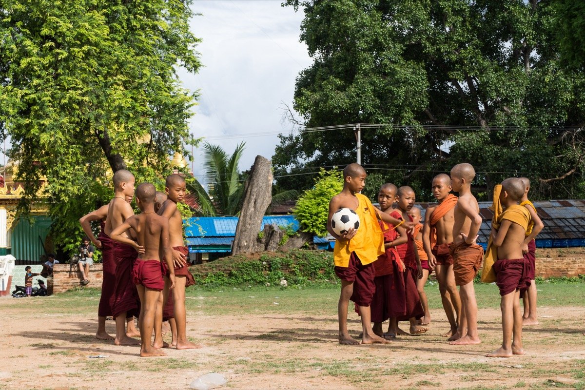 Young monks playing football in front of the pagoda ruins.