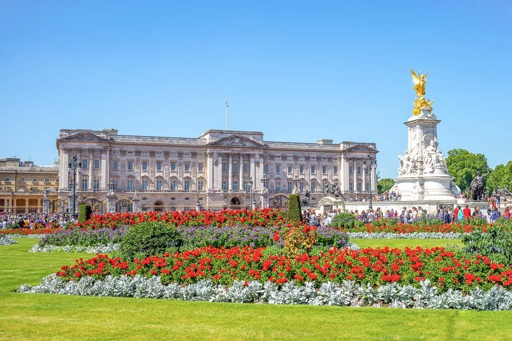 Photo of Buckingham Palace with the striking red tulip garden in the foreground cleverly obscuring the throngs of tourists.