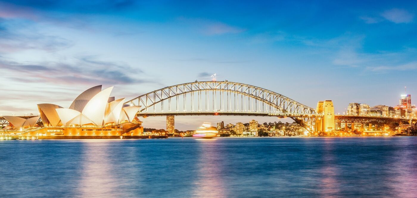 View of illuminated Sydney Opera House and Harbour Bridge at dawn
