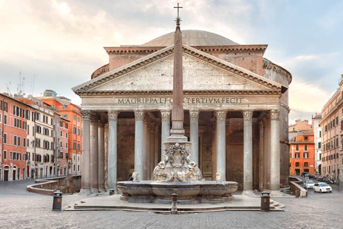 The Pantheon in Rome is a colonnaded stately building, in front of it is a fountain with obelisk