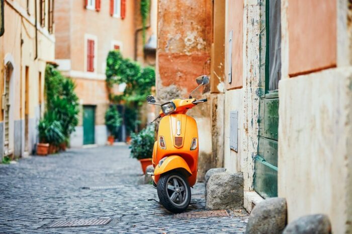 Orange Vespa on a cobbled street in Trastevere, Rome