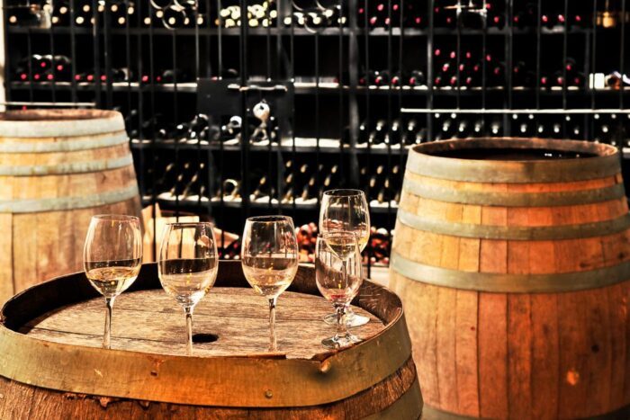 wine glasses on wine barrels, with wine bottles in the background