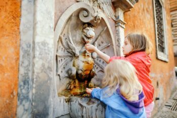 Children playing at a water fountain in Rome